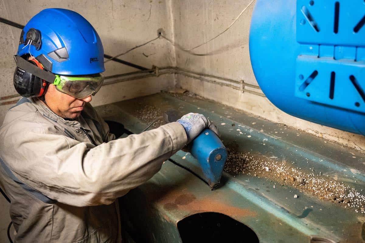 Technicien équipé de protections réalisant la découpe d’une cuve à fioul à l’aide d’un outil spécialisé